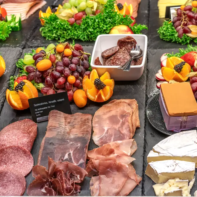 Frokostbuffén byr på spekemat, ulike oster, druer, appelsiner, bær og tilbehør som sur agurk m.m.
