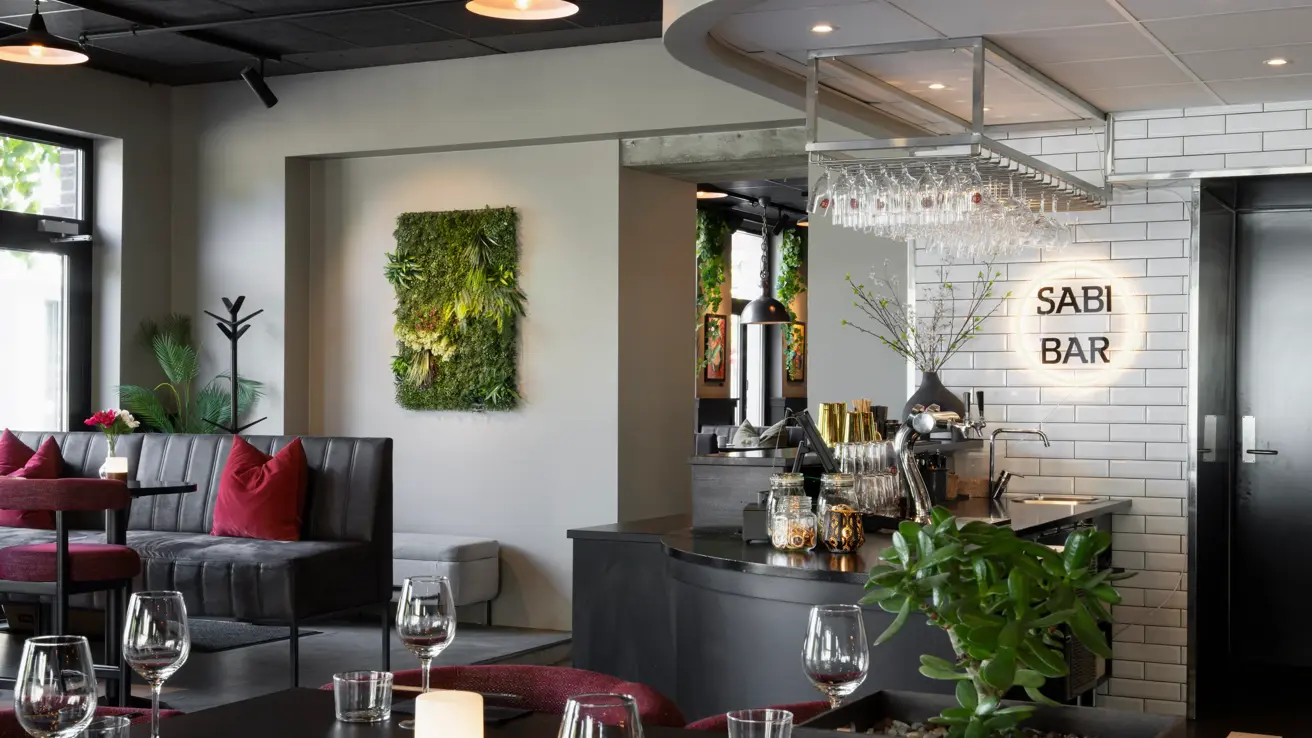 Flere sittplasser i restauranten med sorte bord og stoler, med rosa puter