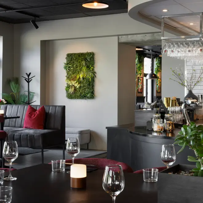 Flere sittplasser i restauranten med sorte bord og stoler, med rosa puter