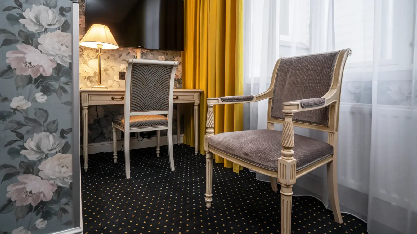 TV, tapetvegg, skrivebord, to stoler, vindu, gule gardiner