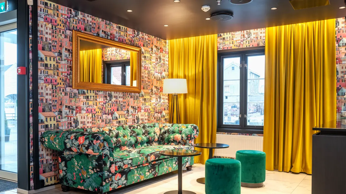 Gule gardiner, to grønne puffer, sofa med møsnter, tapetvegg med mønster, vindu