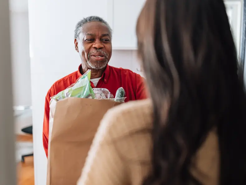 Mann som mottar en pose med mat