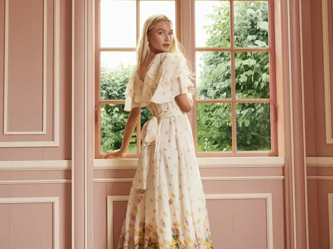 Dame som står ved et vindu og ser på kameraet