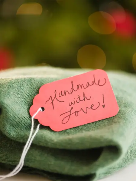 Grønn hjemmelaget genser med navnelapp hvor det står "handmade with love"