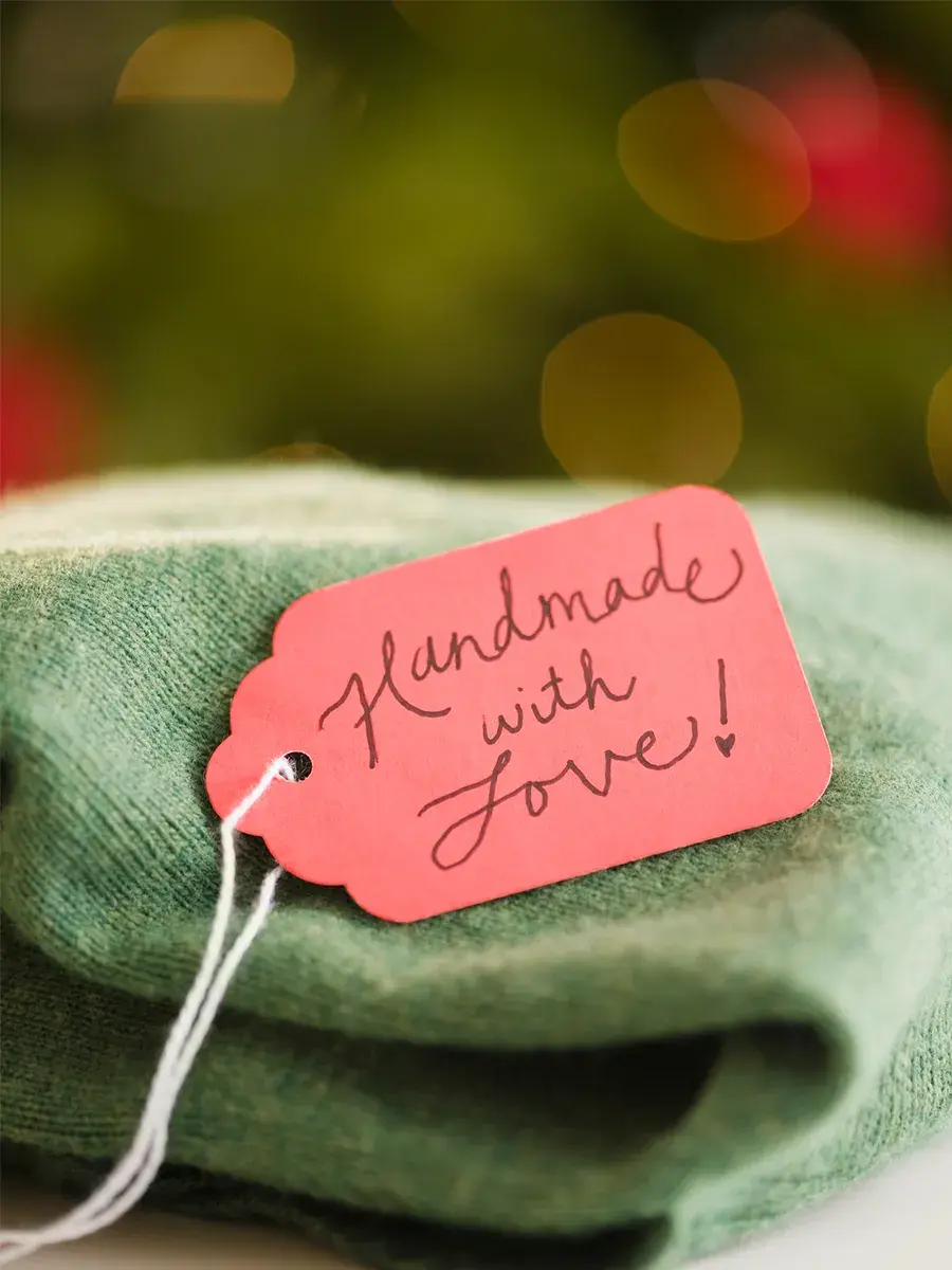 Grønn hjemmelaget genser med navnelapp hvor det står "handmade with love"