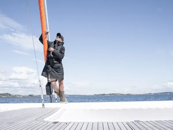 Person ute på båt i regnklær i solværet