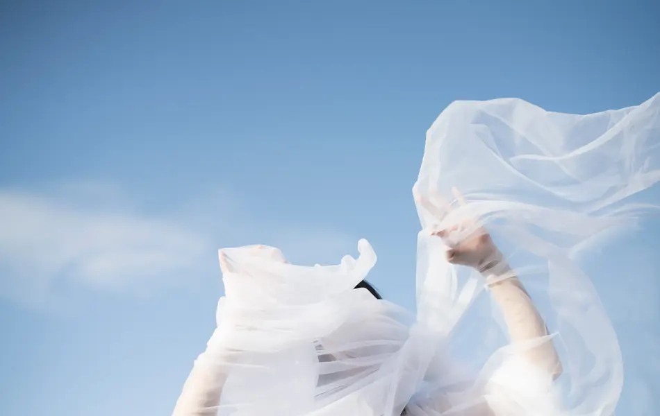 Dame vaier flagrende tynt stoff i luften med blå himmel i bakgrunnen