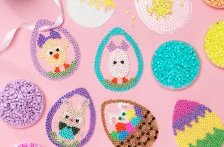 Ulike perle påskeegg ligger på et bord med rosa duk