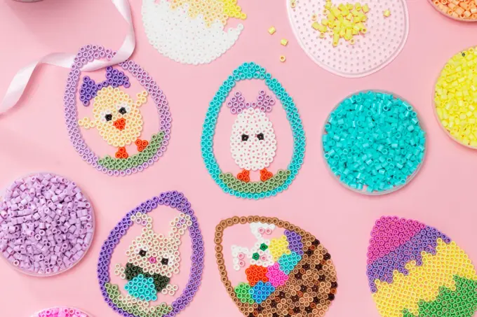 Ulike perle påskeegg ligger på et bord med rosa duk