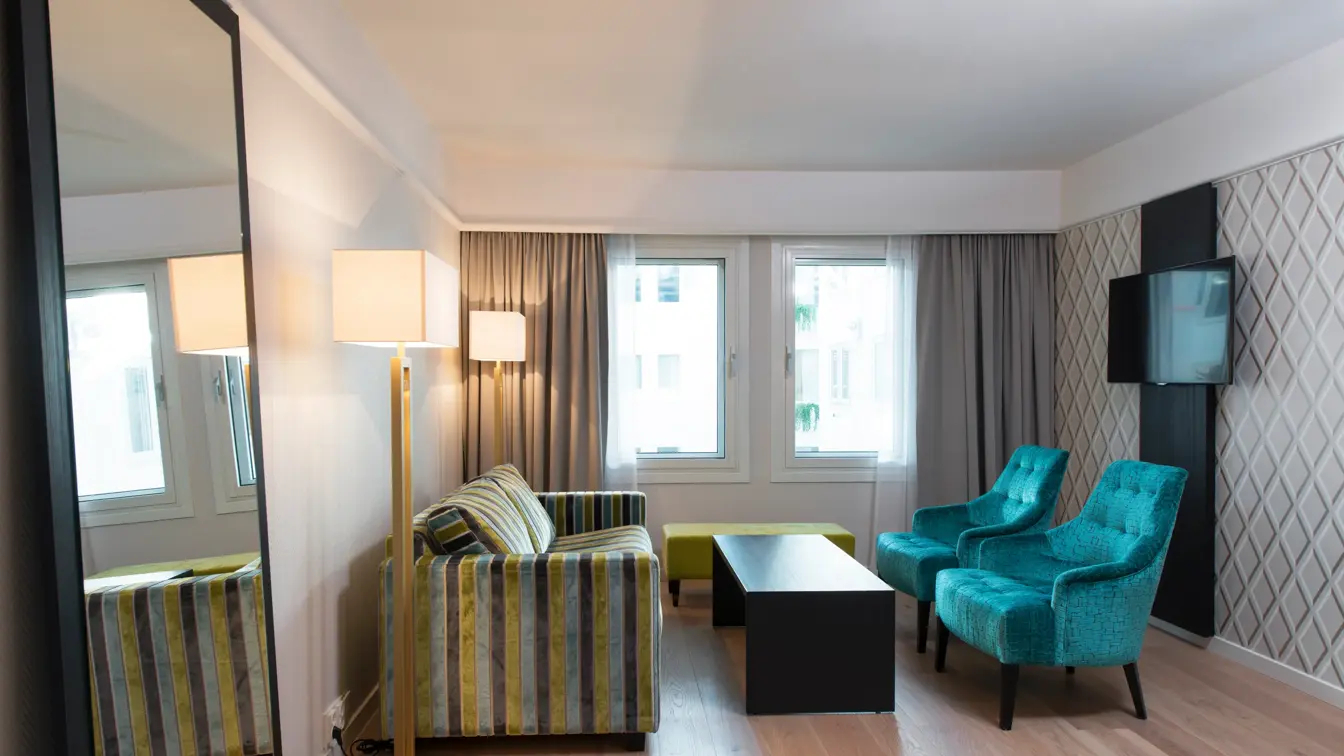 To lenestoler, sofa og stort speil og tv på veggen  i business room på Thon Hotel Oslofjord i Sandvika