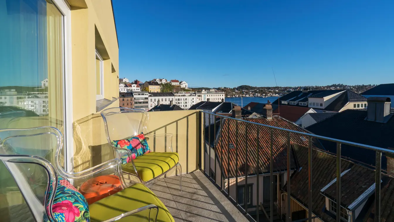 Veranda med utsikt over sjøen og Arendal by med to stoler og ett bord i Suite på Thon Hotel Arendal i Arendal sentrum