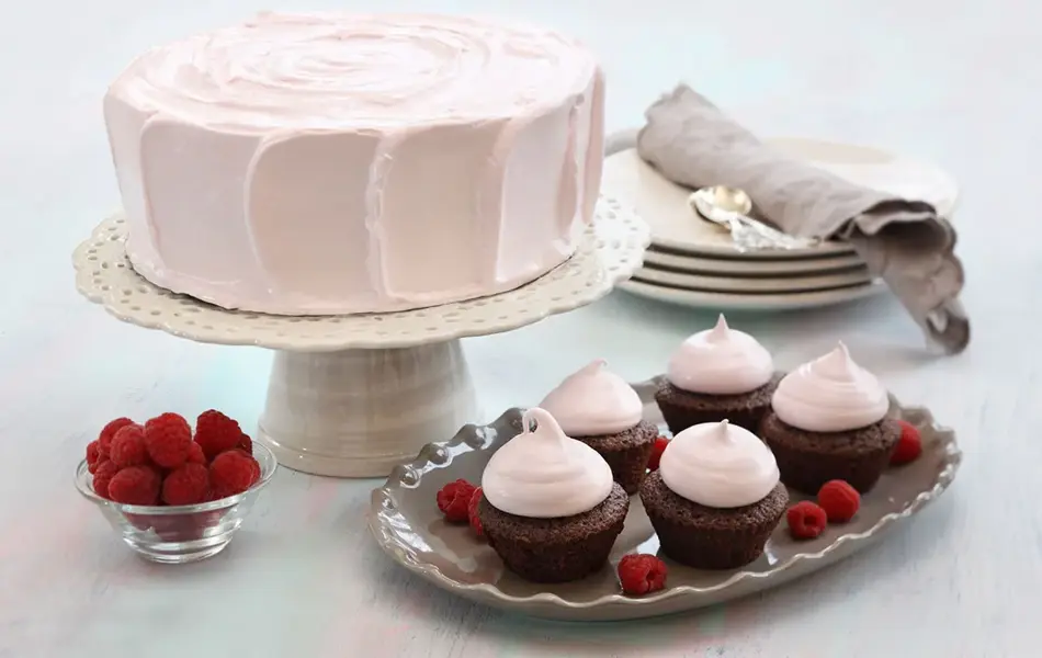 Fem sjokolademuffins med rosa topping ved siden av en rosa kake