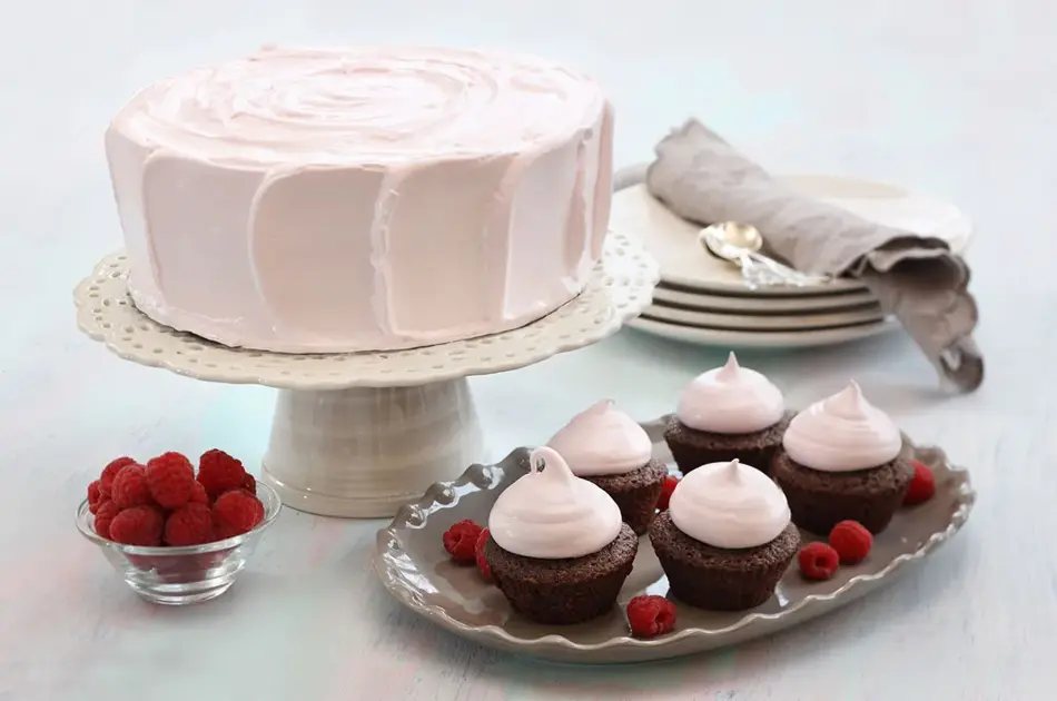 Fem sjokolademuffins med rosa topping ved siden av en rosa kake