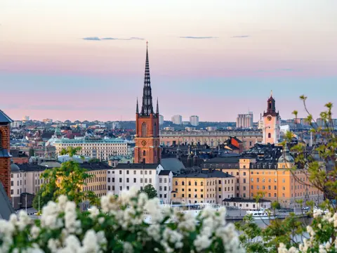 Stockholm cityscape showing historic buildings and riddarholmen church spire against a colorful sky