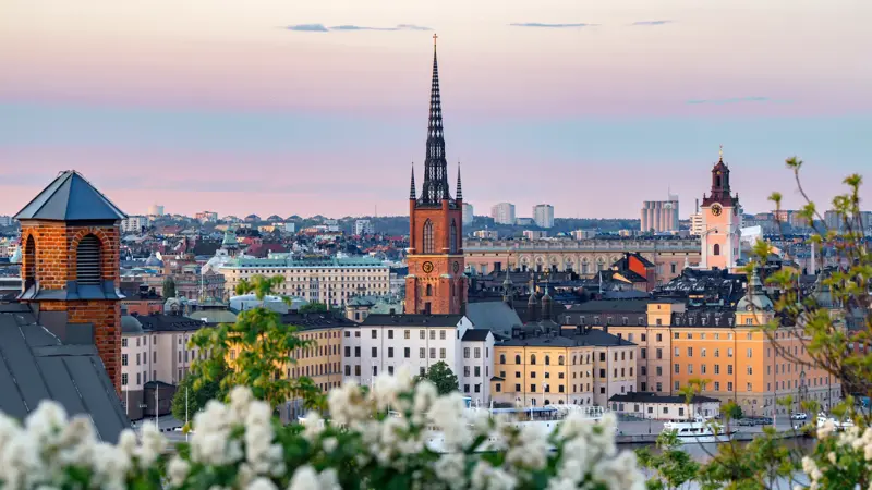 Stockholm cityscape showing historic buildings and riddarholmen church spire against a colorful sky