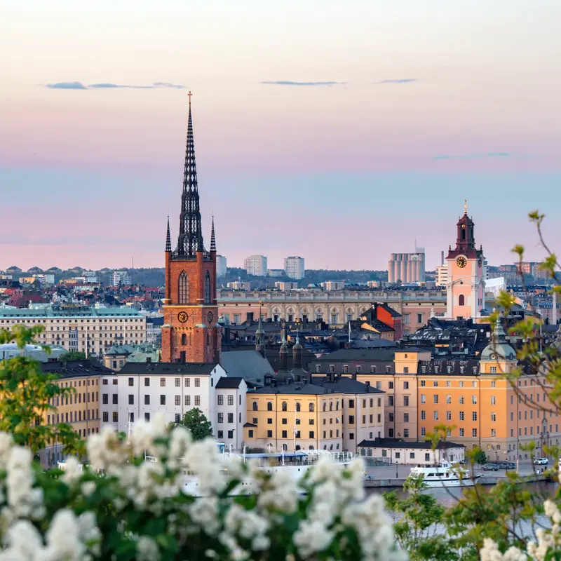 Stockholm cityscape showing historic buildings and riddarholmen church spire against a colorful sky