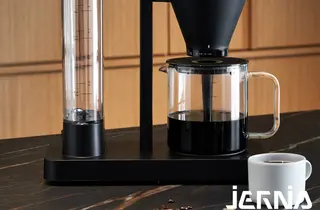 Sort kaffetrakter med glasskanne og kaffekopp.
