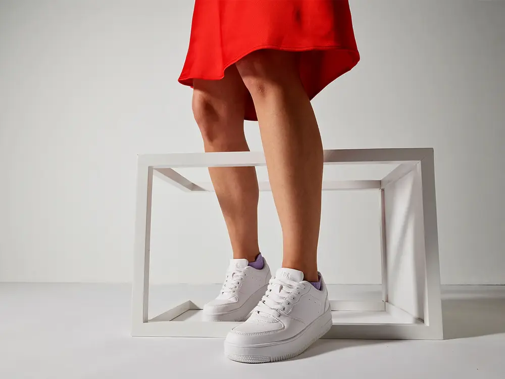 dame med rødt skjørt og hvite sneakers