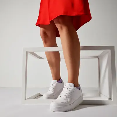 dame med rødt skjørt og hvite sneakers