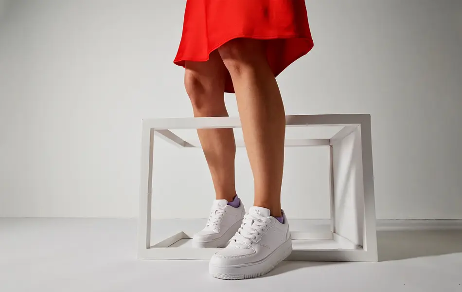 dame med rødt skjørt og hvite sneakers