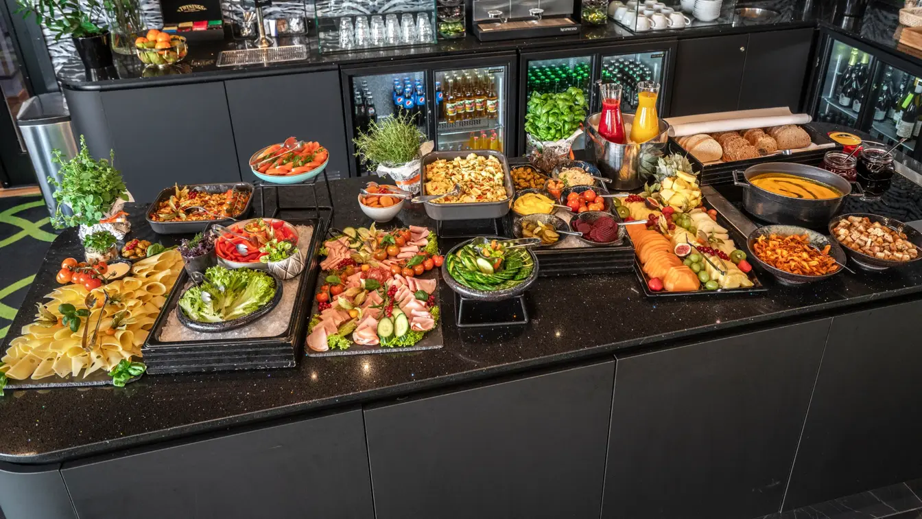 Kveldsmat på buffet med diverse pålegg, fargerike grønnsaker og oppkuttet frukt, smoothie og brød.