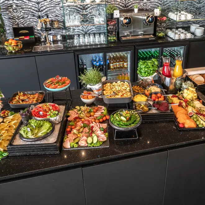 Kveldsmat på buffet med diverse pålegg, fargerike grønnsaker og oppkuttet frukt, smoothie og brød.