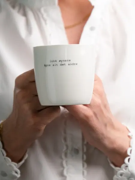 En dame som holder på med oppussing og tips om interiør trender for våren 2021. Damen har lyst halvlangt hå og har på seg en blå olaskjorte og blå olabukse. Fargene går i brunt og beige jordtoner og det er mye lilla og pastellfarger