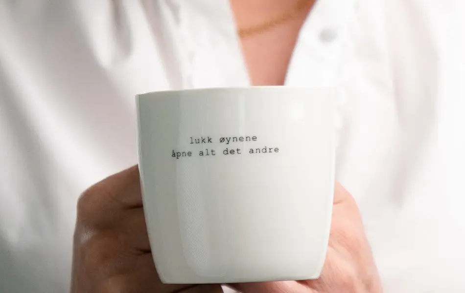 En dame som holder på med oppussing og tips om interiør trender for våren 2021. Damen har lyst halvlangt hå og har på seg en blå olaskjorte og blå olabukse. Fargene går i brunt og beige jordtoner og det er mye lilla og pastellfarger