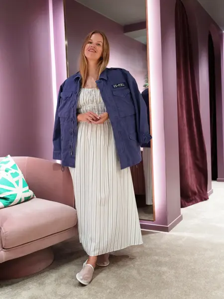 Damemodell med lang stripete kjole og blå jakke