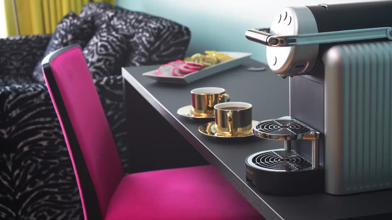 Skrivepult med kaffemaskin, lilla stol og zebramønstret sofa ved siden av på suite på Thon Hotel Terminus i Oslo sentrum nær Jernbanetorget