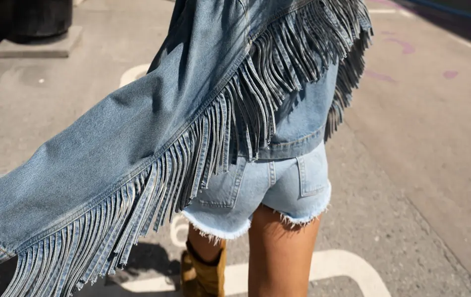 Jente går ute med olajakke med frynser og kort olashorts