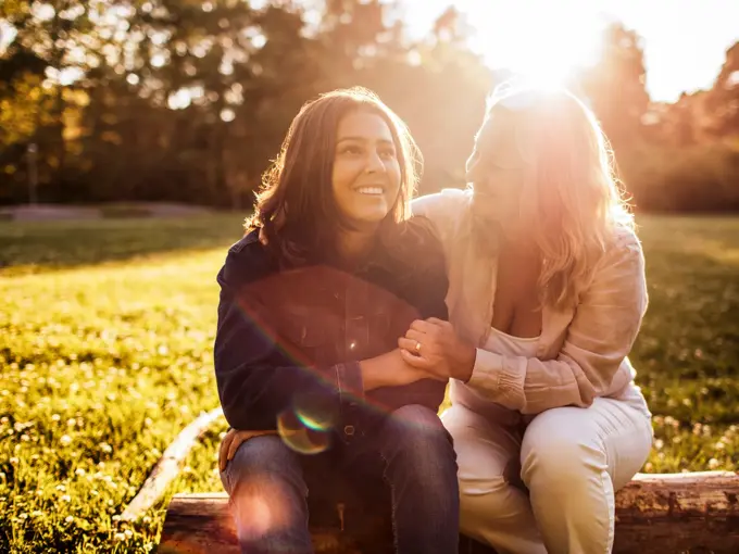Mor og datter sitter ute på benk med solnedgang