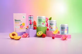 Fem forskjellige produkter fra Bloom står på sokler med frukt rundt.