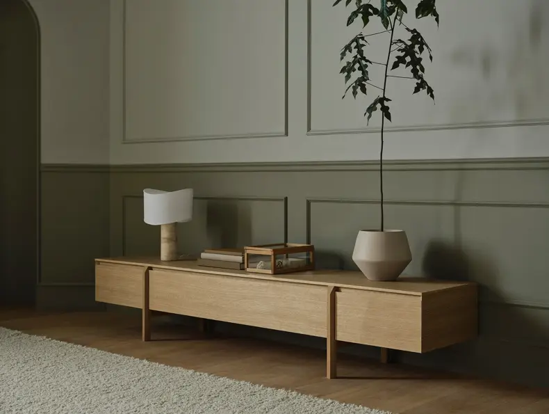 TV-benk i lyst tre med bordlampe, bøker og plante i krukke.