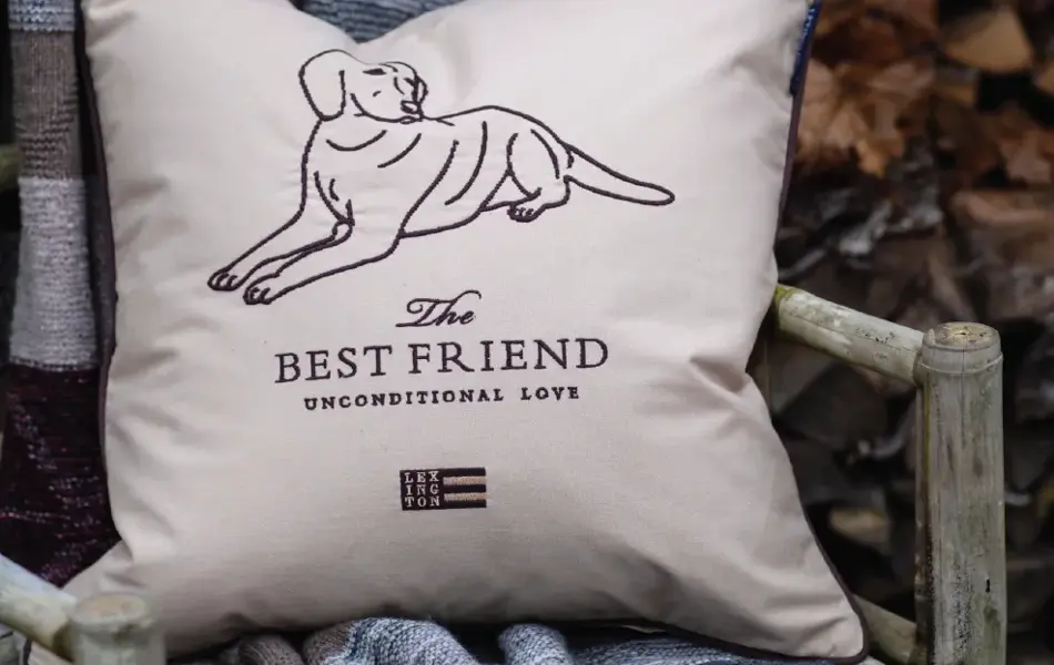 Hagestol dekket med pledd og pute med hund og teksten "The best friend"