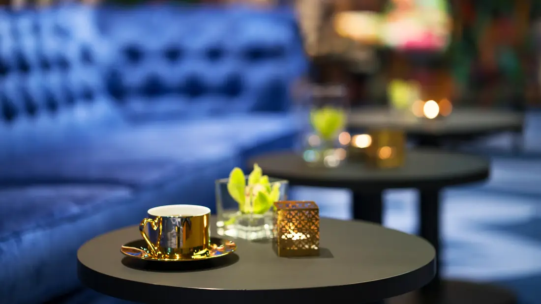 Blå brede sofaer og gullfarget kaffekopp og orkide på bord i lounge på Thon Hotel Terminus i Oslo sentrum nær Jernbanetorget