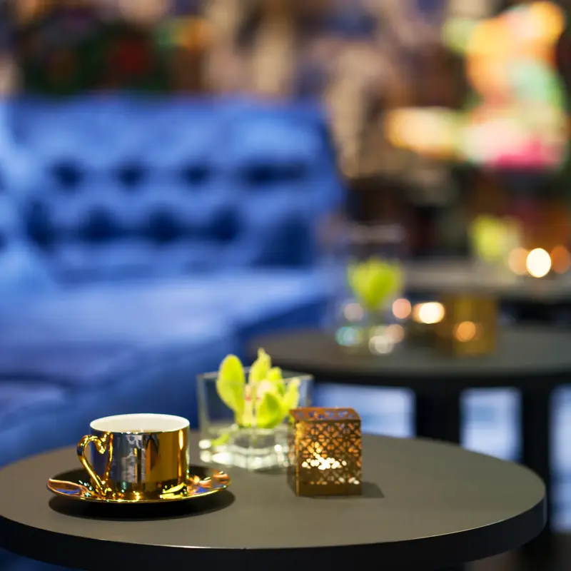 Blå brede sofaer og gullfarget kaffekopp og orkide på bord i lounge på Thon Hotel Terminus i Oslo sentrum nær Jernbanetorget