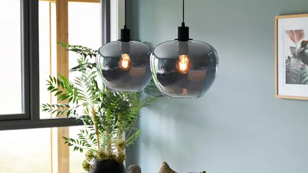 Lampe henger fra taket med maleri i bakgrunn 