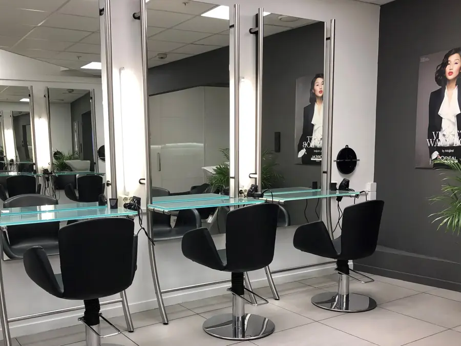 Frisørsalong med fire sorte stoler og speil