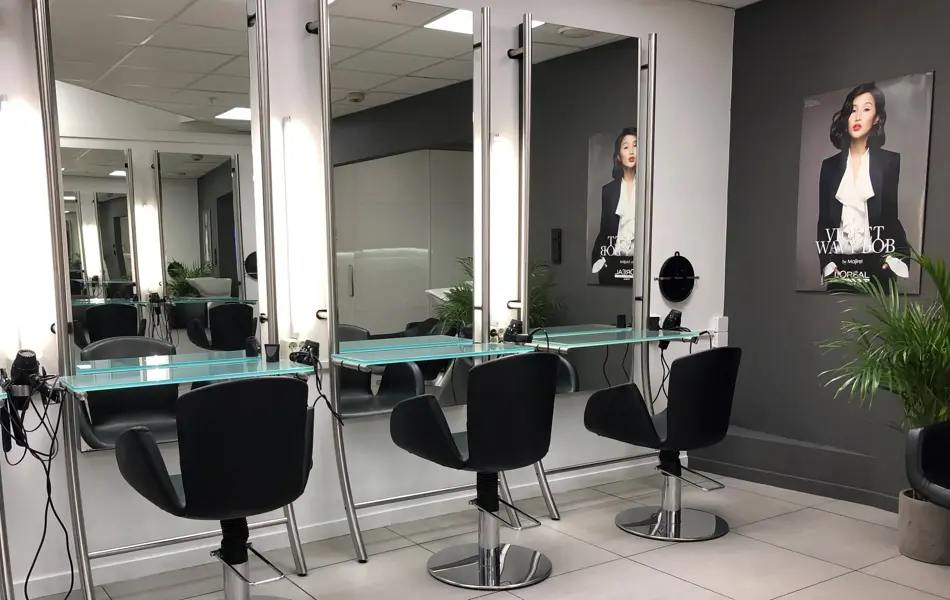 Frisørsalong med fire sorte stoler og speil