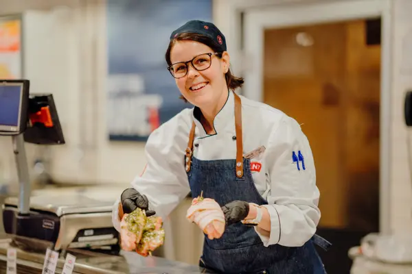 ansatt i fersvaredisken hos Meny holder fram grillmat