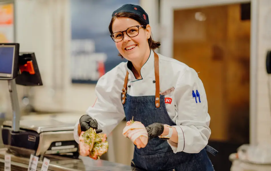 ansatt i fersvaredisken hos Meny holder fram grillmat