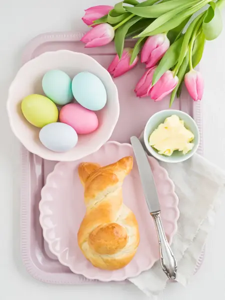Easter breakfast table with Easter eggs, tulips and sweet yeast Easter bunny bread