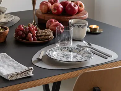 Dekketøy med tallerken, kopp og glass på et bord med frukt og snacks.