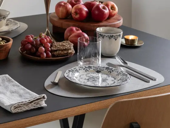 Dekketøy med tallerken, kopp og glass på et bord med frukt og snacks.