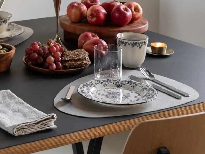 Dekketøy med tallerken, kopp og glass på et bord med frukt og snacks.
