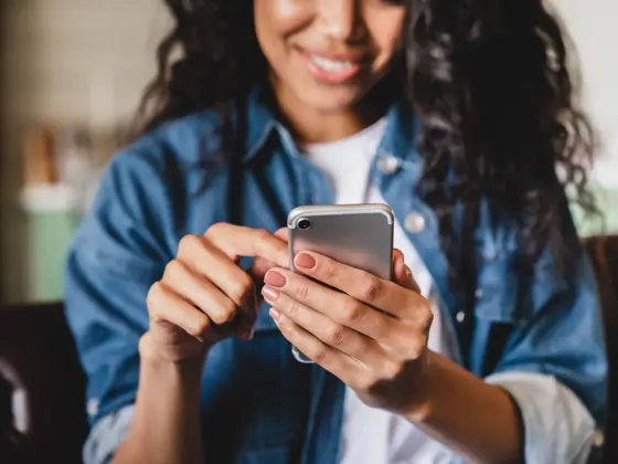 Cropped shot of an african-american young woman using smart phone at home.Smiling african american woman using smartphone at home, messaging or browsing social networks while relaxing on couch