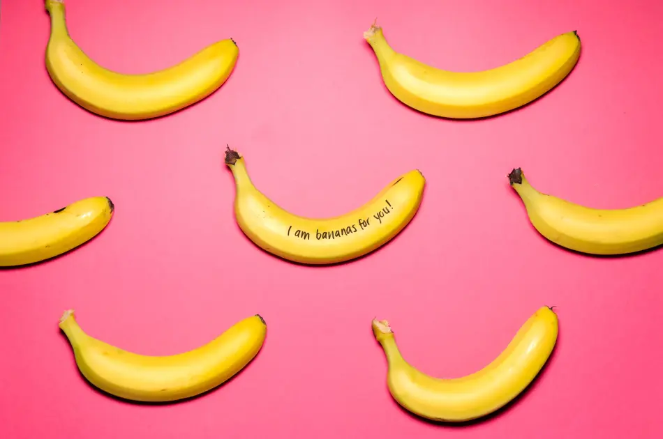 7 gule bananer som ligger på en rosa plate. På den ene bananen står det skrevet med sort tusj" I`m bananas for you"