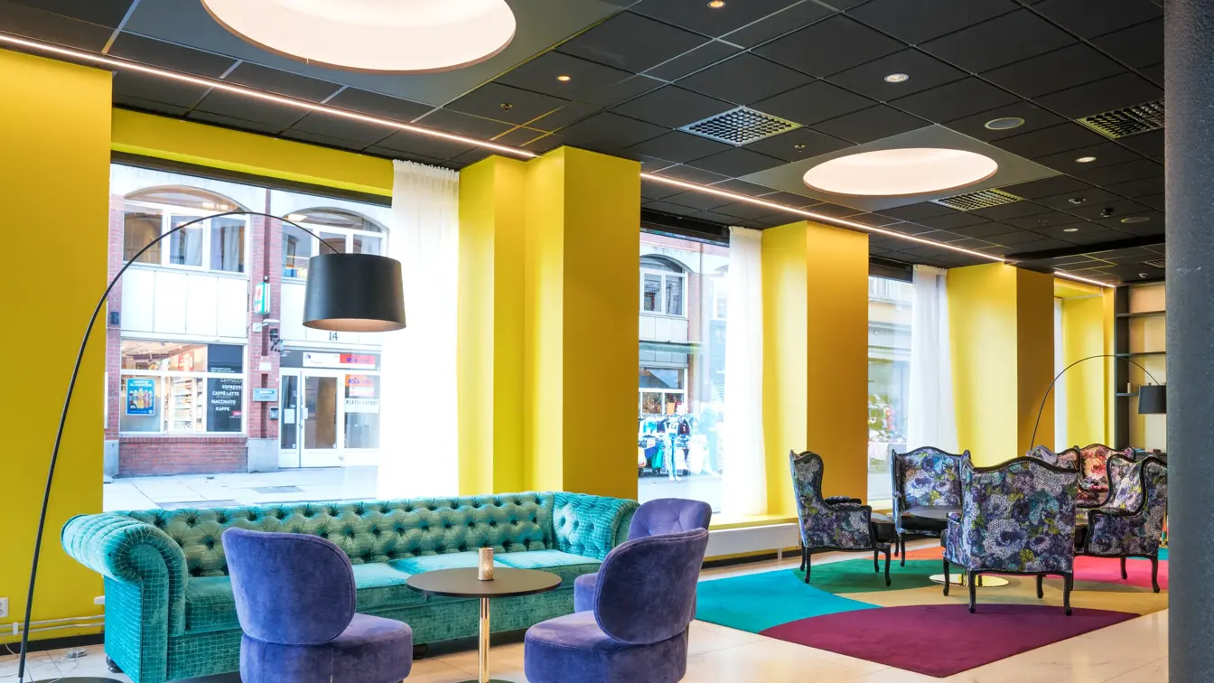 Lobby med fargerikt teppe og blomstermønstrede stoler og stor sofa på Thon Hotel Spectrum i Oslo sentrum