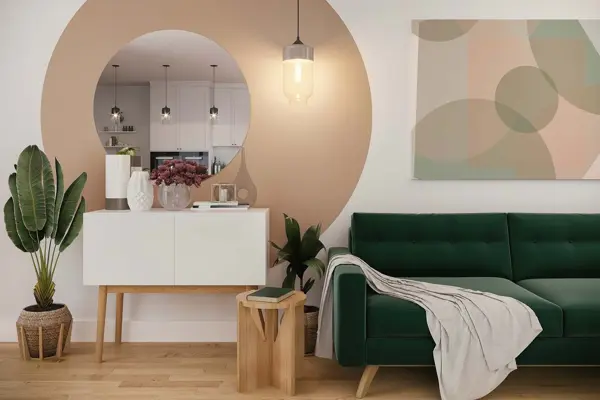 Interiørfoto med planter, velursofa, skap, malt sirkel på veggen, sirkelformet speil, bilde på veggen med sirkler. Duse farger i grønn, naturtre, hvitt og pudder. Interiørtrend vår 2022.